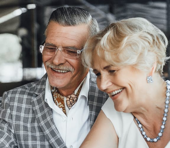 Well dressed mature couple sitting outside at a restaurant looking at a computer together